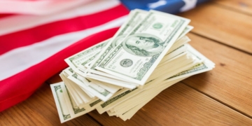 Stimulus check money in cash with an American Flag