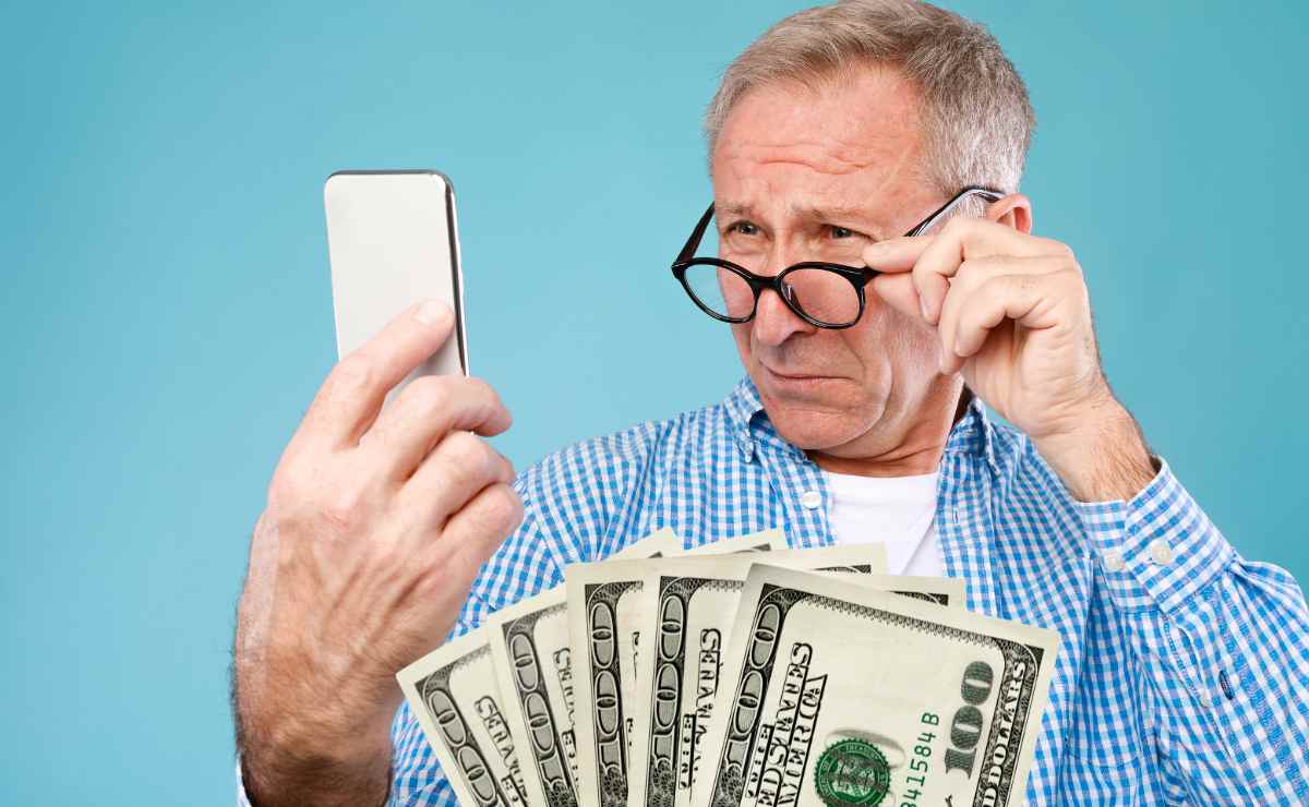 Senior looking a t his mobile phone to talk about SSI payments in October 2023