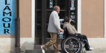Asistente empujando a persona con discapacidad en silla de ruedas