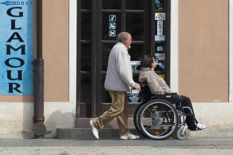 Asistente empujando a persona con discapacidad en silla de ruedas