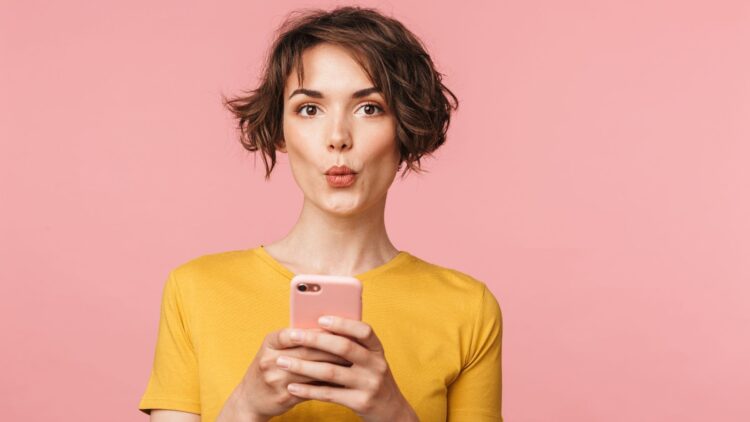 Mujer sorprendida con un teléfono móvil en la mano
