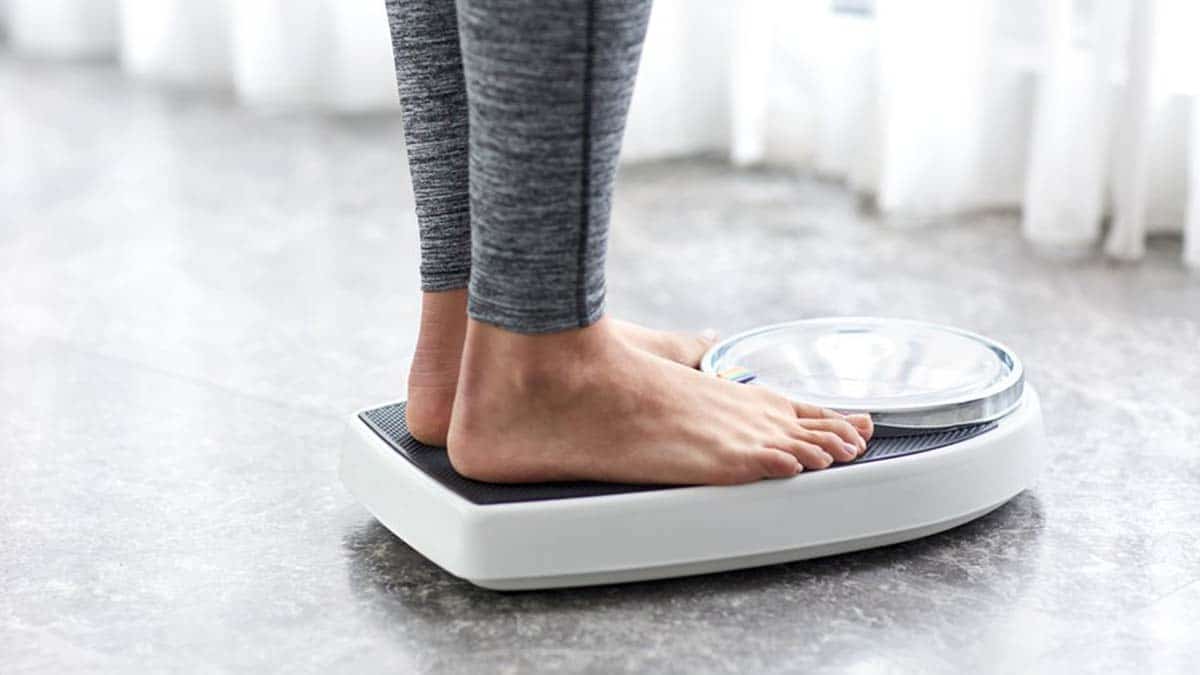 Una persona pesándose para comprobar si logra bajar de peso
