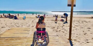 Niña de 7 años en su silla de ruedas en la pasarela playa