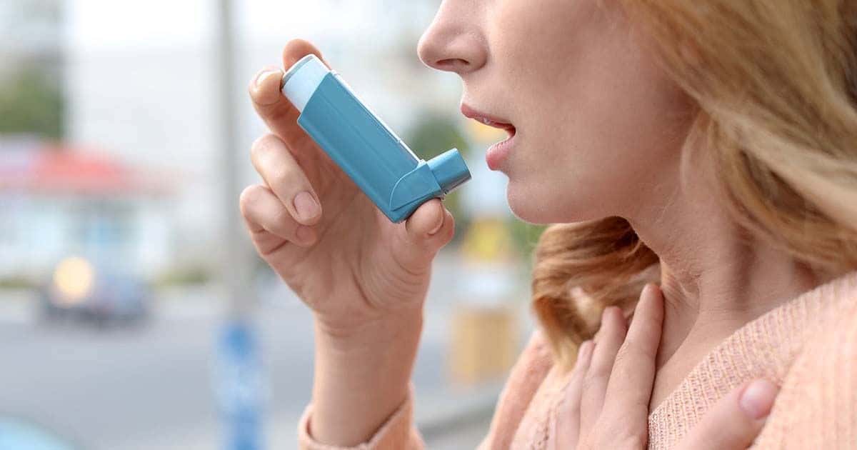 Mujer con asma usando un inhalador