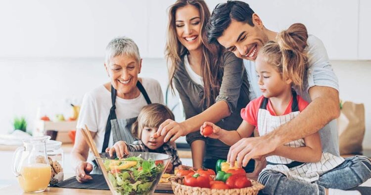 Three-generation family with two small children preparing food.