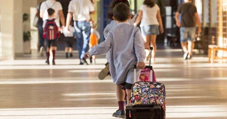 Niño empujando su maleta con ruedas