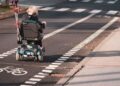 Persona en silla de ruedas eléctrica circulando por la calzada