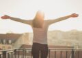 Mujer con brazos abiertos mirando al sol. Calidad de vida