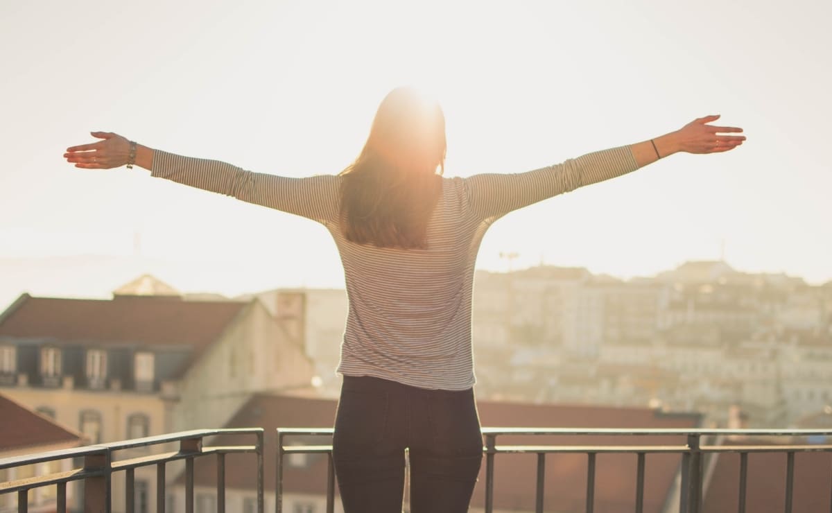 Mujer con brazos abiertos mirando al sol. Calidad de vida