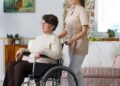 Mujer mayor con discapacidad en silla de ruedas junto a su asistente personal - ley dependencia