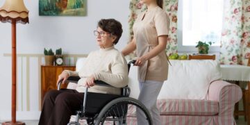 Mujer mayor con discapacidad en silla de ruedas junto a su asistente personal - ley dependencia