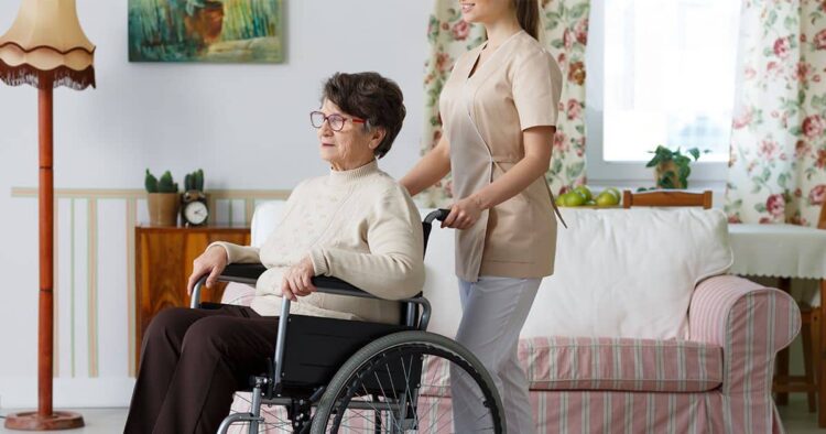 Mujer mayor con discapacidad en silla de ruedas junto a su asistente personal - ley dependencia