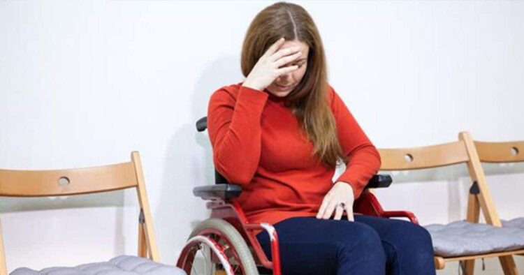 Mujer en silla de ruedas tocándose la cabeza discapacidad