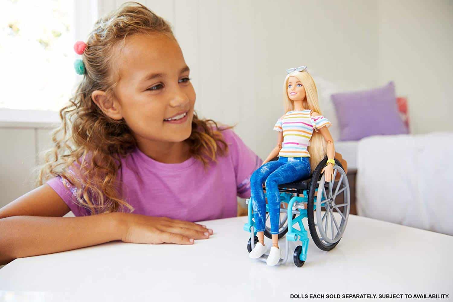 Niña jugando con la barbie silla de ruedas