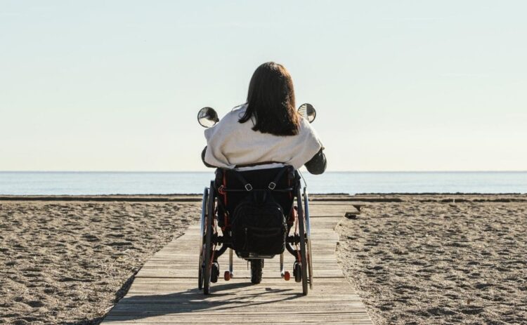 Una mujer en silla de ruedas pasea por una playa de Oropesa del Mar, nuevo destino de Turismo Accesible