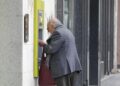 Una persona mayor saca dinero en un cajero de una entidad bancaria