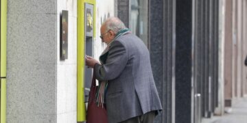 Una persona mayor saca dinero en un cajero de una entidad bancaria