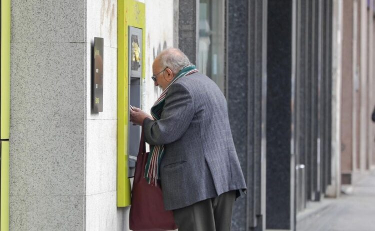 Una persona mayor saca dinero en un cajero de una entidad bancaria