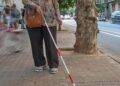 Persona sordociega, con discapacidad visual, con un bastón blanco y rojo