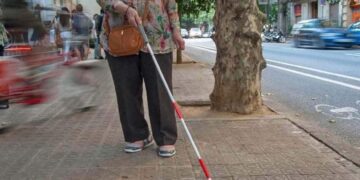 Persona sordociega, con discapacidad visual, con un bastón blanco y rojo