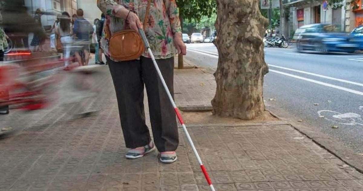 Persona sordociega, con discapacidad visual, con un bastón blanco y rojo