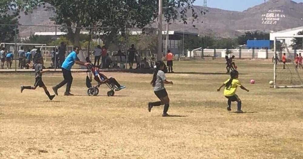 Un padre empuja la silla de ruedas de su hijo para que pueda jugar al futbol