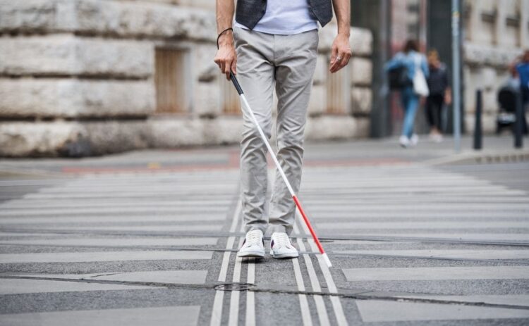 Persona ciega con discapacidad visual cruza un paso de peatones accesible accesibilidad ONCE
