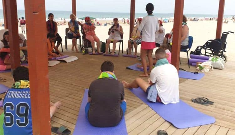 varias personas haciendo yoga en la tarima de la playa