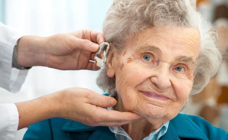 Un profesional coloca el audífono a una persona mayor