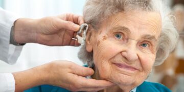 Un especialista coloca el audífono a una persona mayor