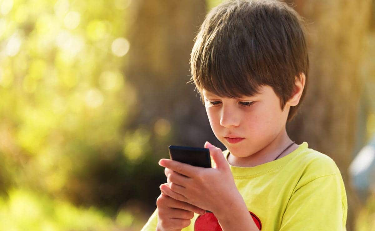 Niño mirando la pantalla del móvil (CANVA)