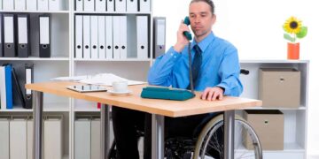 hombre en silla de ruedas junto a mesa escritorio discapacidad empleo publico