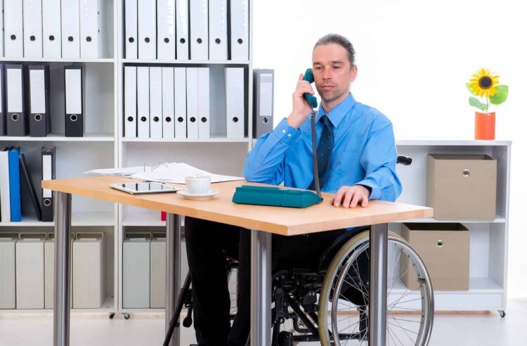 hombre en silla de ruedas junto a mesa escritorio discapacidad empleo publico