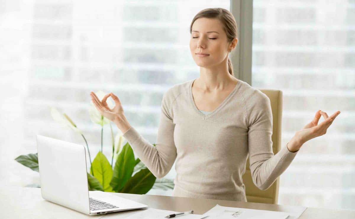 Una mujer con estrés meditando en su puesto de trabajo