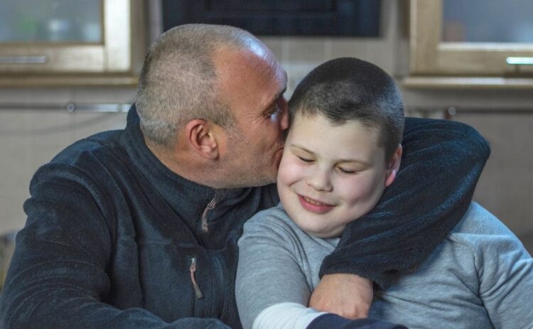 Padre besa y abraza a su hijo con autismo