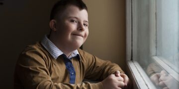 Joven con Síndrome de down en la ventana