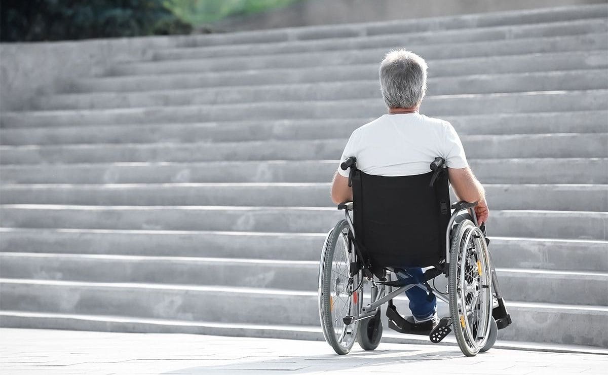 Una persona en silla de ruedas con discapacidad se encuentra una escalera que no es accesible