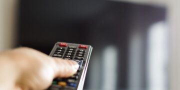 Persona con el mando a distancia en la mano para activar los subtítulos