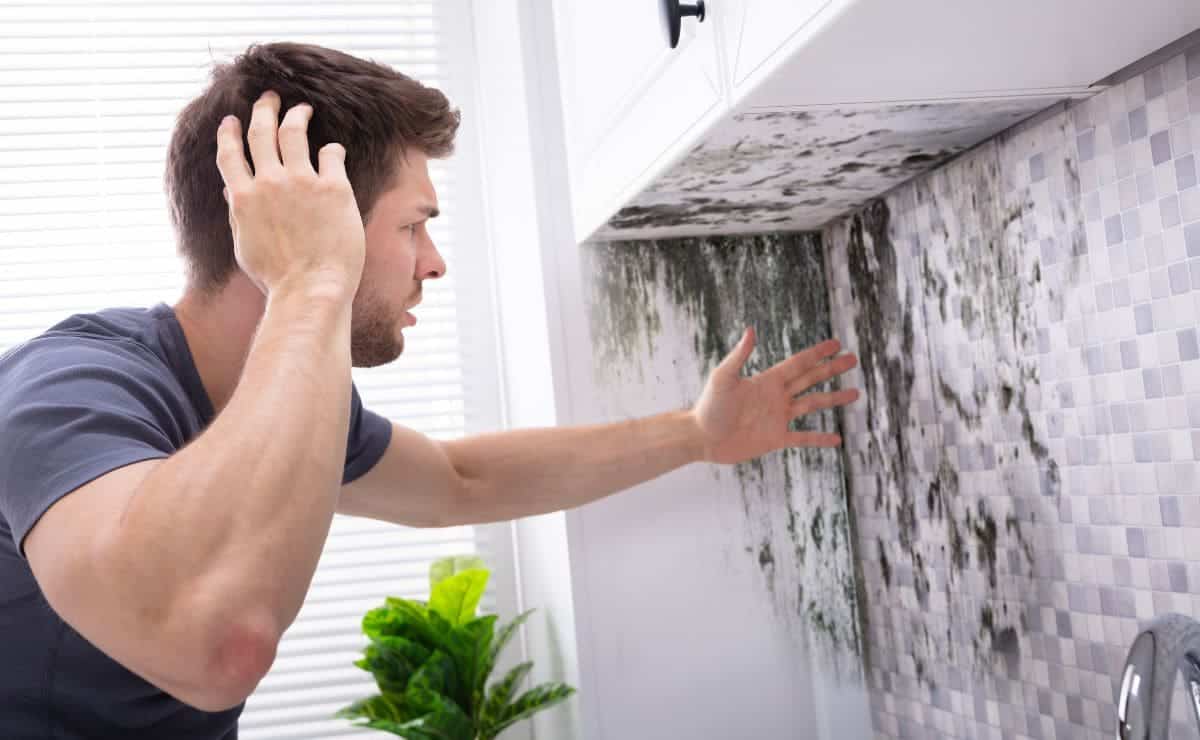 Hombre mirando una pared con moho de la humedad 