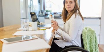 Mujer con discapacidad en silla de ruedas trabajando frente al ordenador