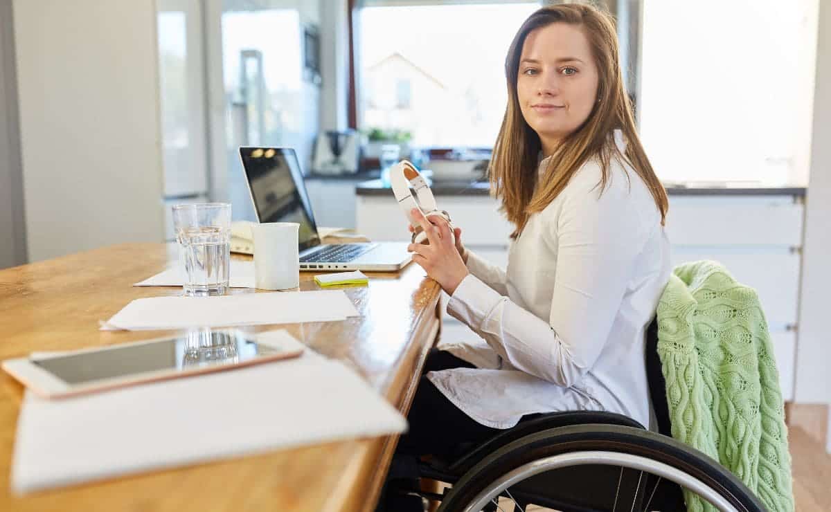 Mujer con discapacidad en silla de ruedas trabajando frente al ordenador