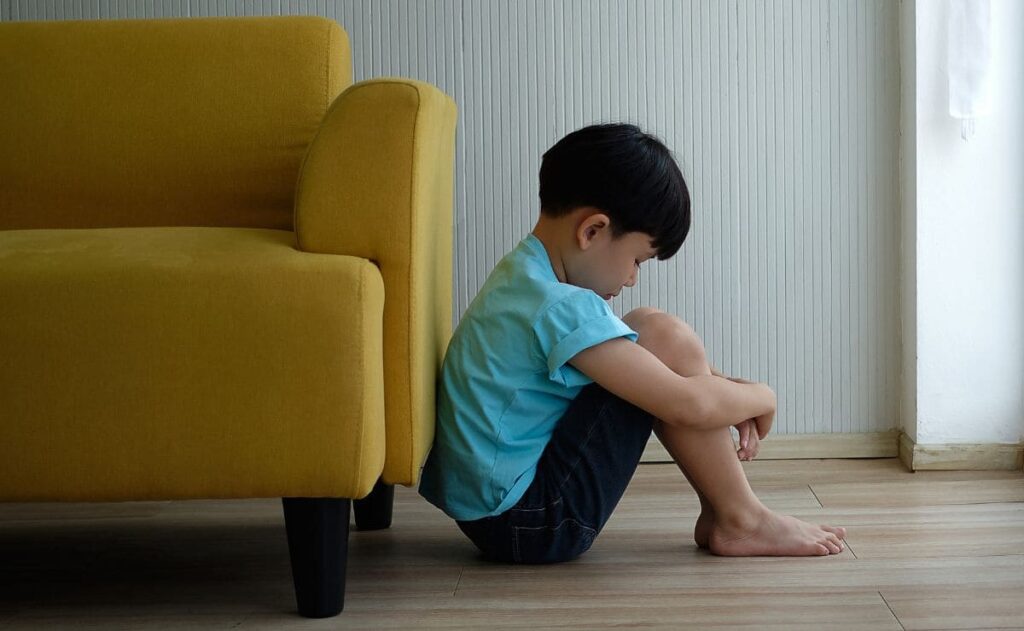 Niño pequeño con autismo sentando en el suelo