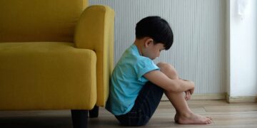 Niño pequeño con autismo sentando en el suelo