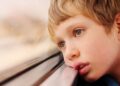 Niño con autismo mira por la ventana