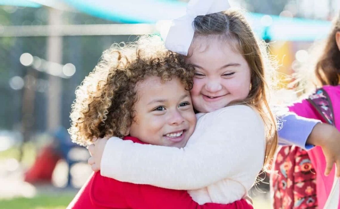 Niña con síndrome de Down y su hermana se dan un abrazo