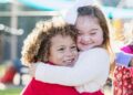 Niña con síndrome de Down y su hermana se dan un abrazo