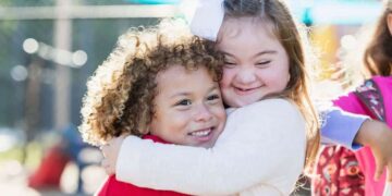Niña con síndrome de Down y su hermana se dan un abrazo