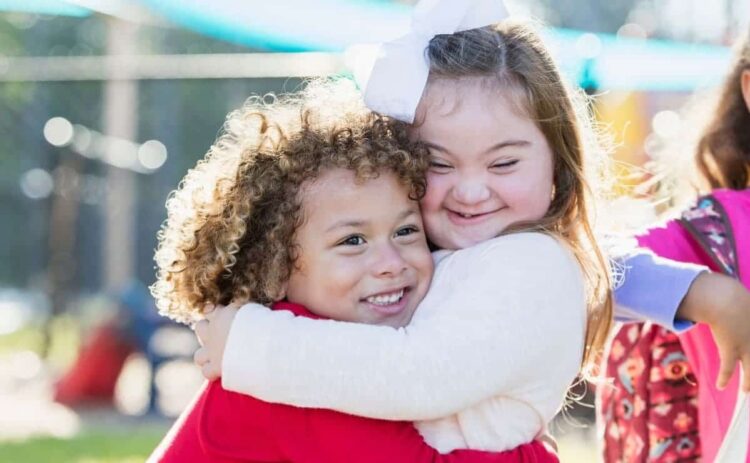 Niña con síndrome de Down y su hermana se dan un abrazo