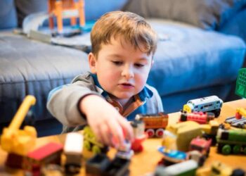 Niño sordo o con discapacidad auditiva jugando con unos coches