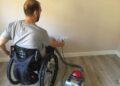 Usuario de silla de ruedas enchufando una aspiradora.